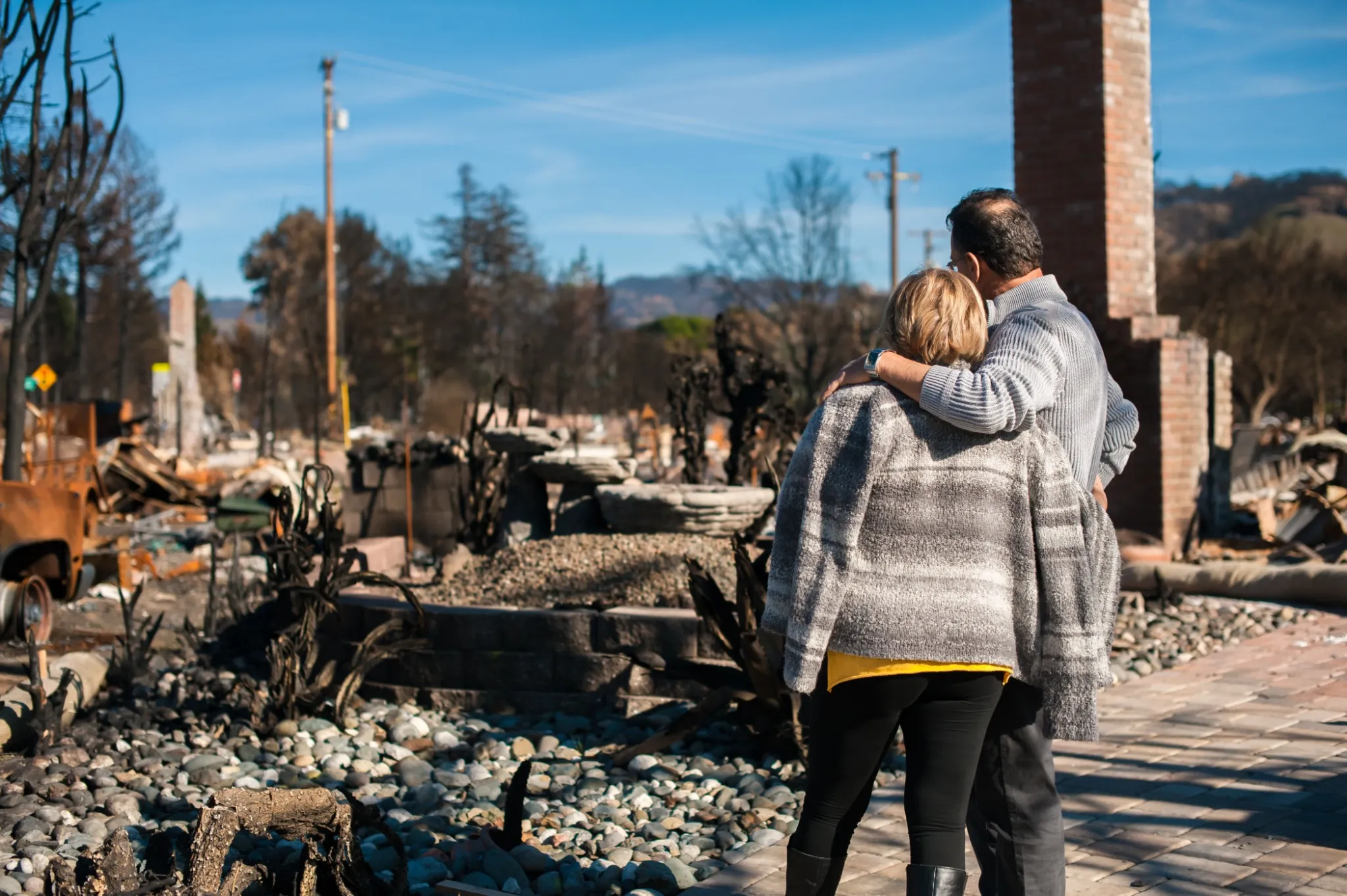 Couple looking at remains of burnt down home